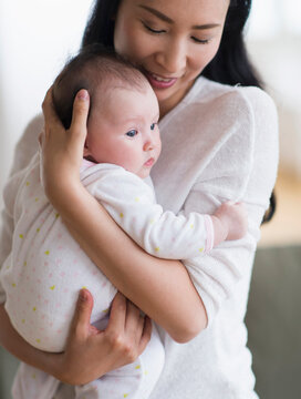 Smiling Asian mother holding baby