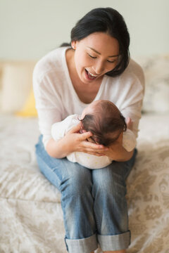 Asian mother holding baby on bed