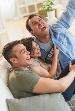 Hispanic friends cheering at television in living room