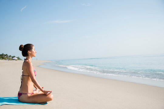 Caucasian woman meditating on beach