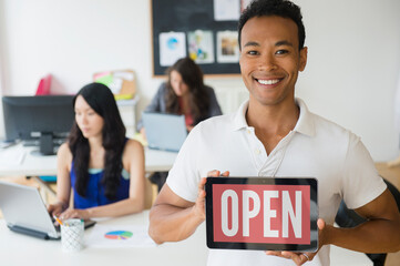 Businessman holding open sign on digital tablet in office