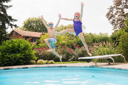 Caucasian children jumping into swimming pool