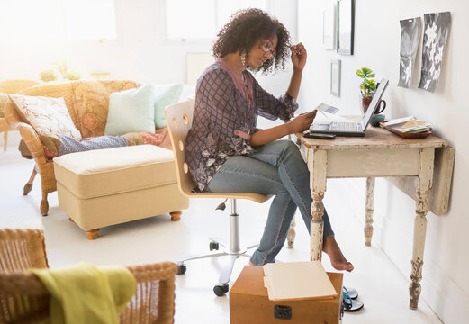 Mixed race woman using laptop in living room