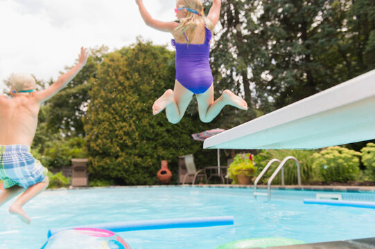 Caucasian children jumping into swimming pool