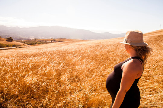 Pregnant Caucasian woman standing in rural meadow