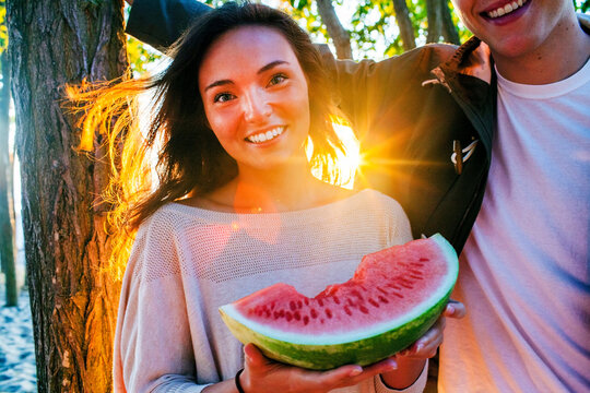 Caucasian couple eating watermelon at sunset