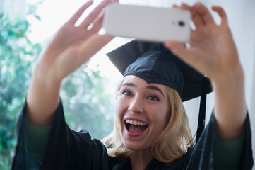 Caucasian student taking cell phone photograph at graduation