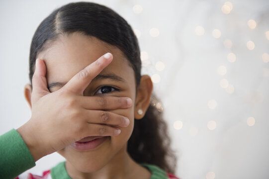 Close up of mixed race girl peeking between fingers