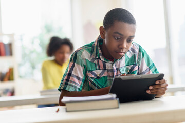 Black student using digital tablet in classroom