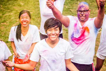 Smiling friends covered in pigment powder cheering