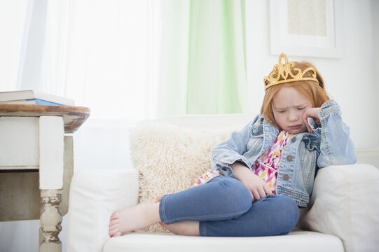 Upset Caucasian girl pouting in armchair