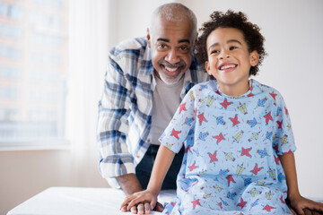 Mixed race grandfather smiling with grandson in hospital