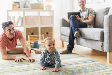 Caucasian gay fathers and baby relaxing in living room