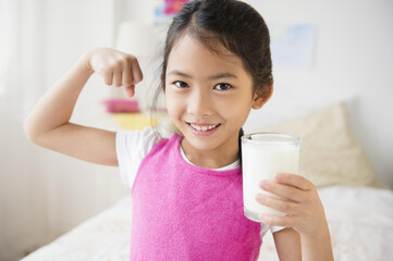 Vietnamese girl flexing muscles with glass of milk