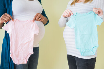 Pregnant women holding boy and girl baby clothes