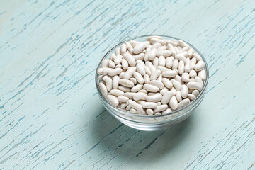 Raw white beans in a bowl on a blue table. Food.