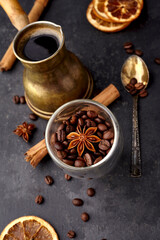 Coffee  with coffee beans, anise, dry orange  and cinnamon on black background. Coffee with spice. Top view.