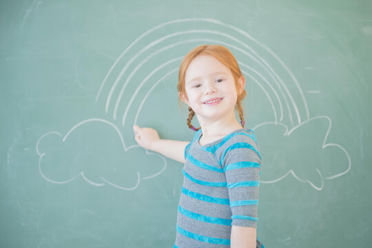 Caucasian girl drawing on chalkboard