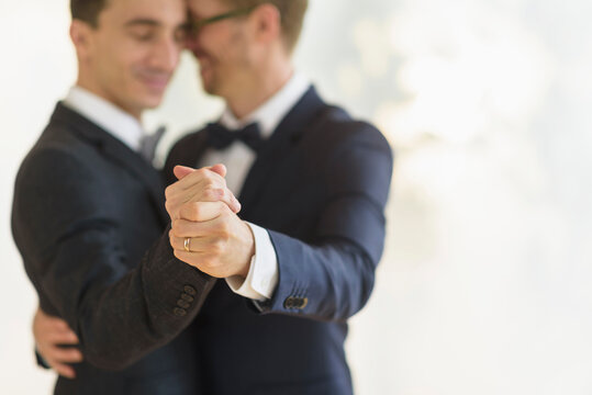 Caucasian gay grooms dancing at wedding