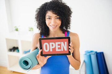 Mixed race woman holding open sign in yoga studio
