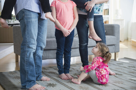 Caucasian girl sitting under family in living room