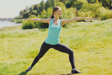 Fitness woman doing exercises on the grass in the summer park