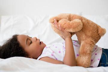 Mixed race girl playing with teddy bear