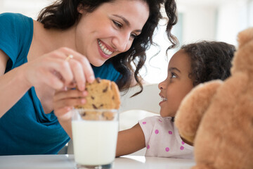 Mother and daughter eating milk and cookies