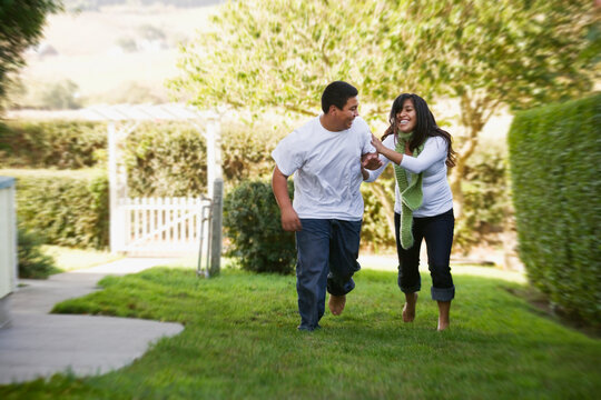 Hispanic brother and sister running on grass