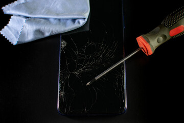 Broken mobile phone (crashed screen) under repair  with selective focus on a black background....