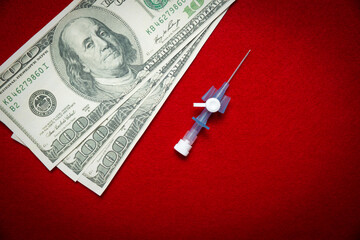 Money and drip needle on a red background. Concept of paying for healthcare.