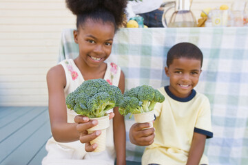 Mixed race children holding broccoli cones