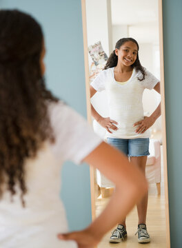 Mixed race girl checking reflection in mirror