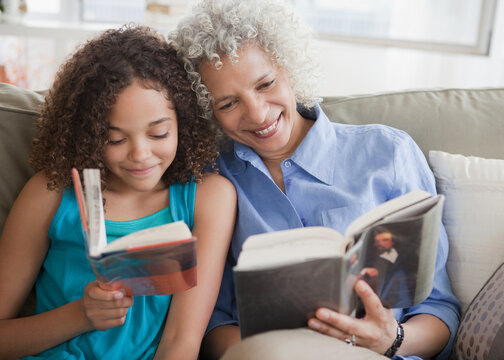 Grandmother and granddaughter reading on sofa