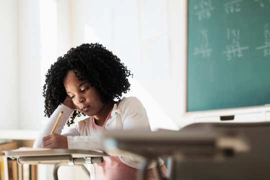 African American student writing in classroom - Powered by Adobe