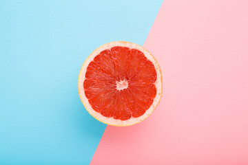One half of bright red grapefruit on light blue pink table background. Fresh fruits. Pastel color....
