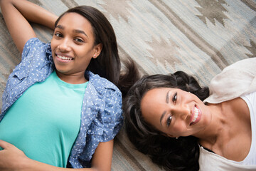 Smiling mother and daughter laying on carpet