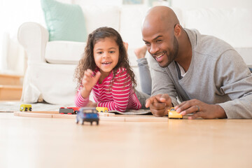 Father and daughter playing with toy cars on floor