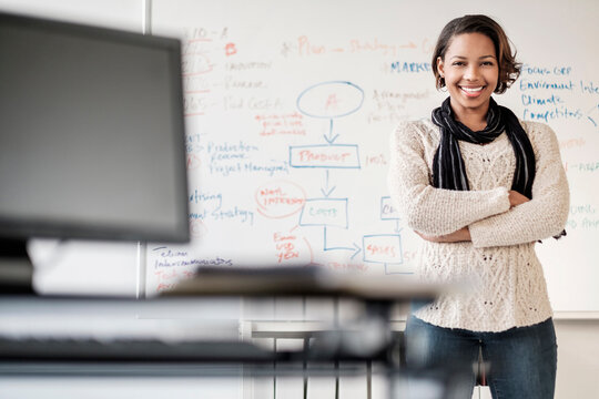 Black businesswoman posing in office near whiteboard