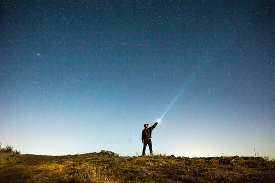Caucasian man pointing flashlight at night sky