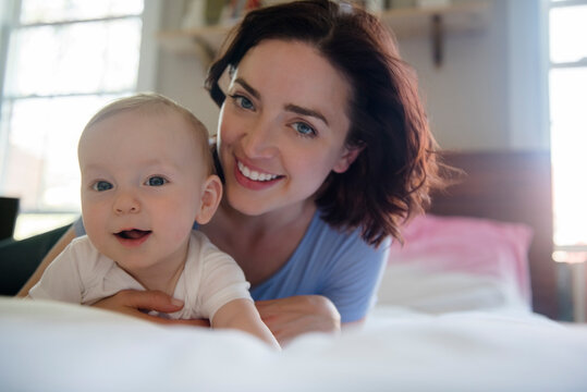 Caucasian mother smiling with baby son on bed