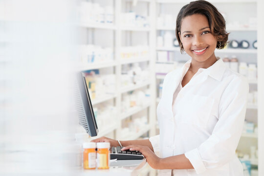 Smiling Black pharmacist using computer