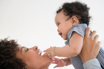 Mother lifting baby son face to face