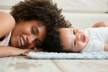 Mother and baby son laying head to head on floor