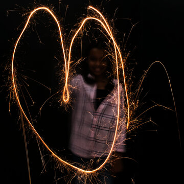Mixed Race girl making heart-shape with sparkler