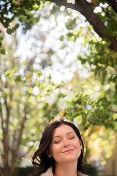 Caucasian woman with eyes closed under tree