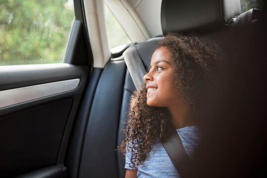 Smiling Hispanic girl in car looking out window