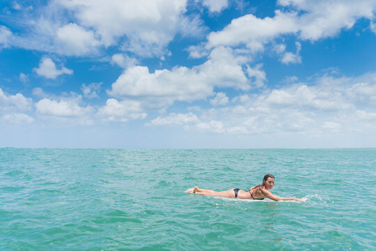 Caucasian woman paddling on surfboard in ocean