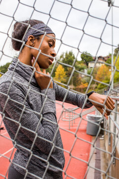 Black woman behind chain-link fence checking pulse