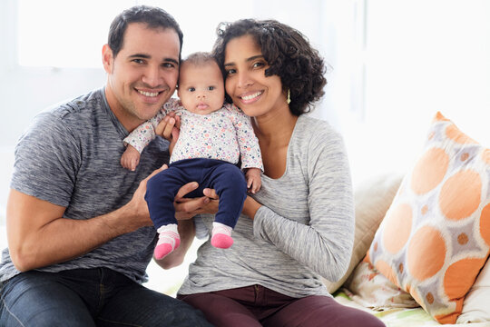 Hispanic mother and father posing with baby daughter